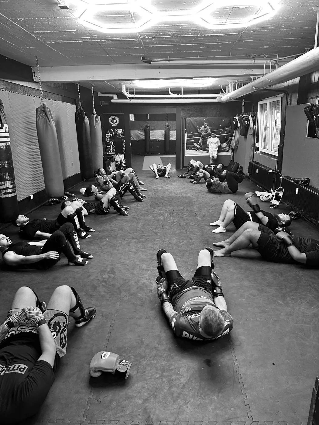 Trainingsraum von Comeback Sports mit Sandsäcken an den Wänden und Mattenboden, Mitglieder machen Bauchübungen